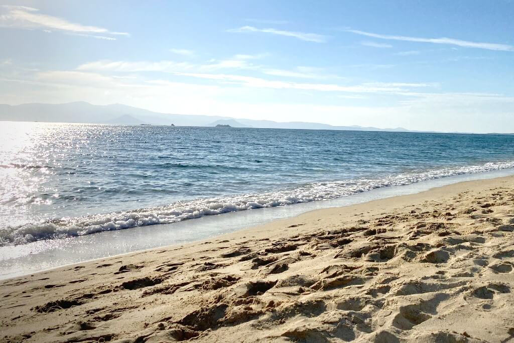 a sandy beach with small waves washing the coast