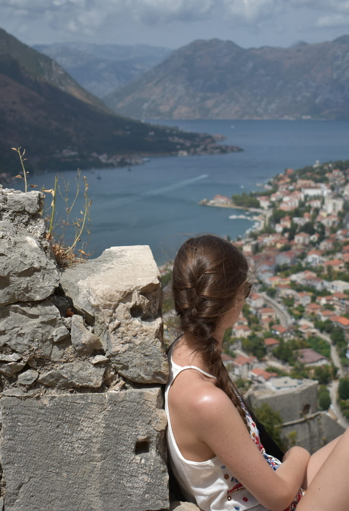 a girl overlooking kotor cove with a french braid hairstyle