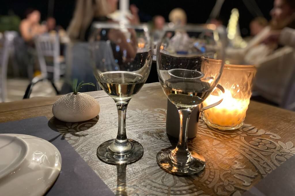 two glasses of wine on a table with a candle burning in the back in parikia paros seafront restaurant