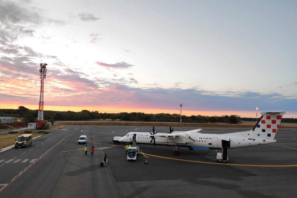 photo of a croatian airlines small airplane on pula airport with the sunrise in the background