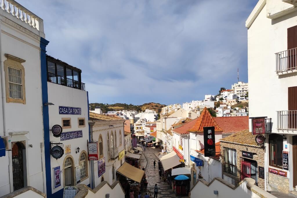 city centre of albufeira with white houses and a cobblestone street with stands