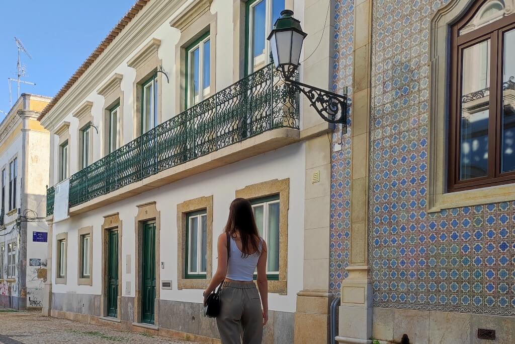 natali walking away from the camera in front of tiled buildings in faro, algarve