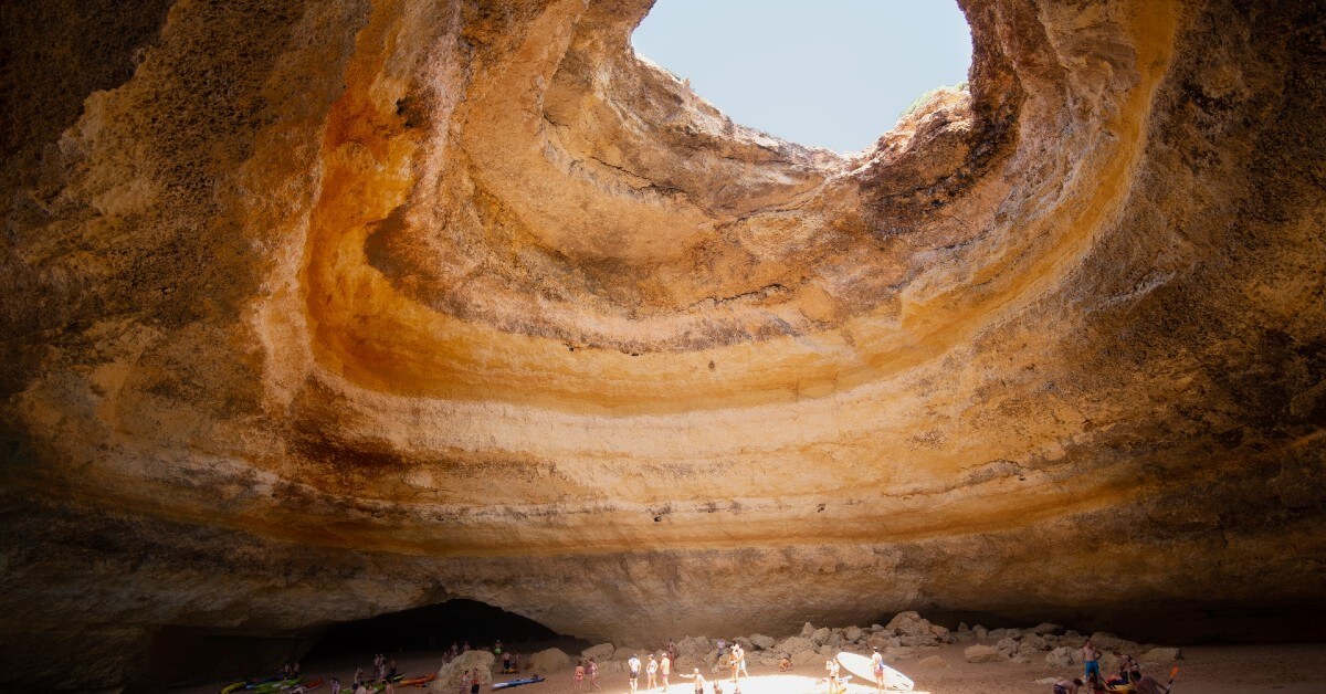 a photo of a sea cave with ceiling opening - benagil cave