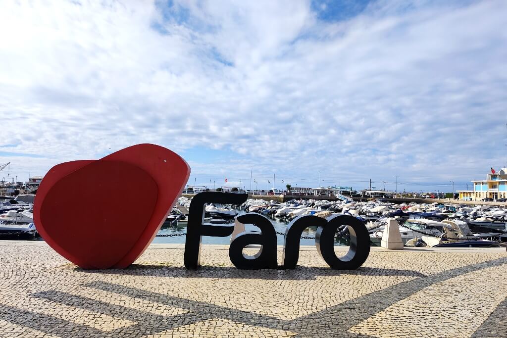 red heart sculpture and black letter faro with faro marina in the background