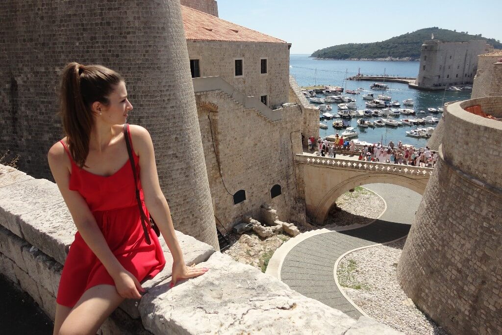 natali in a red dress looking at dubrovnik old city wallls