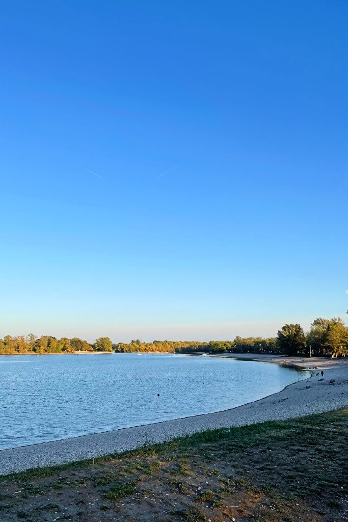 jarun lake zagreb beach with small white pebbles and trees in the background