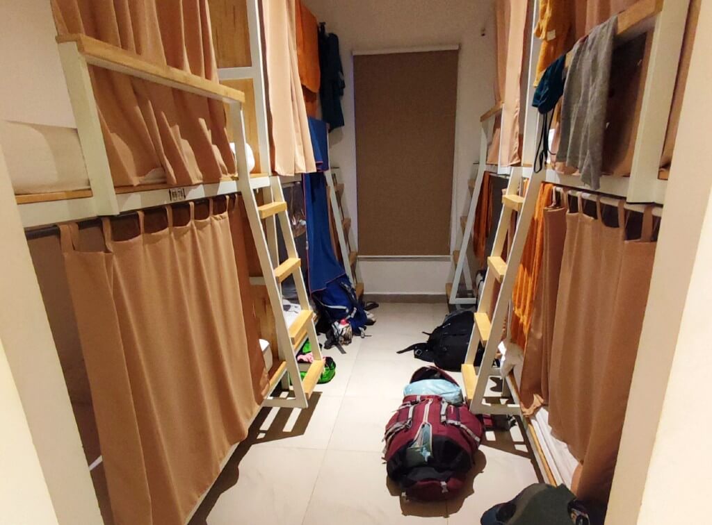 dorm room in a kampot hostel with beige privacy and backpackas on the floor