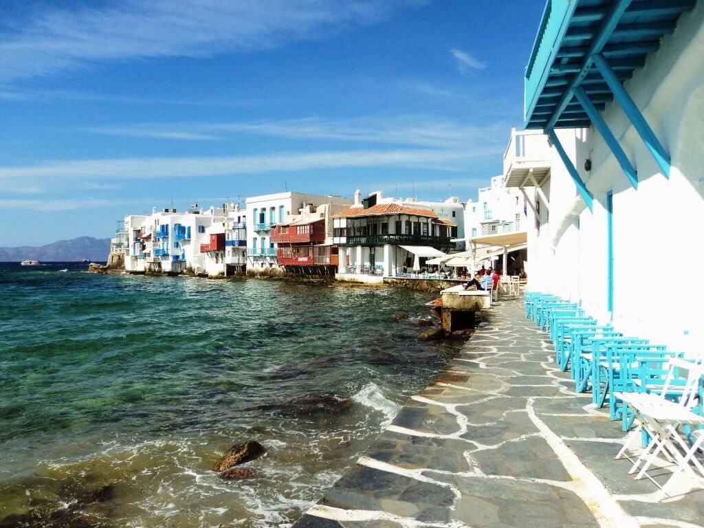 little venice in mykonos with its iconic wooden chairs, tables, white houses with colorful doors