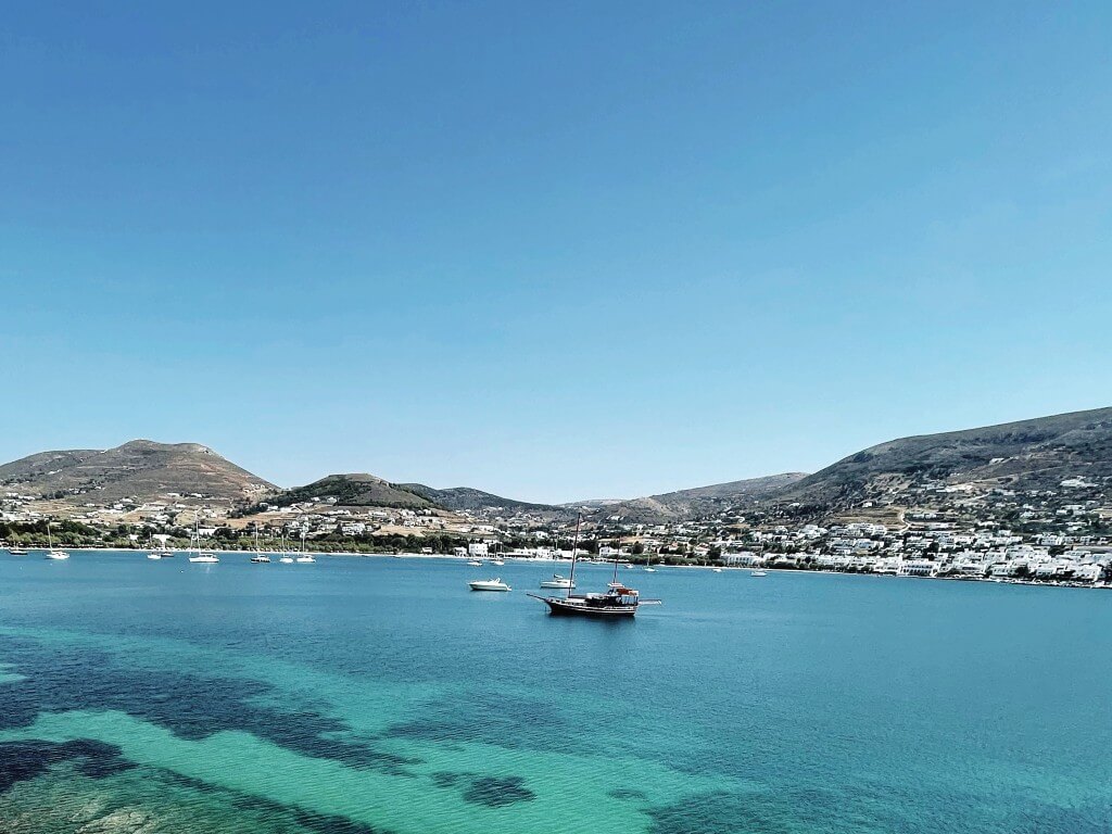 view of paros coastline from antiparos and sailboats in the vibrant blue sea