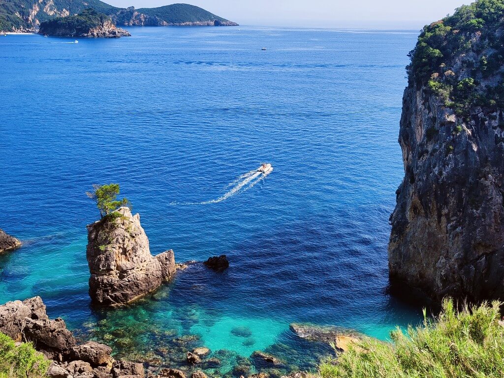 a small boat sailing on clear turqouise sea in corfu