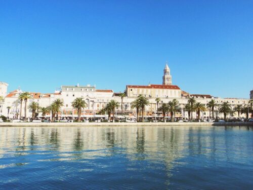 seafront promenade in split croatia with buildings reflecting in the sea on a sunny day