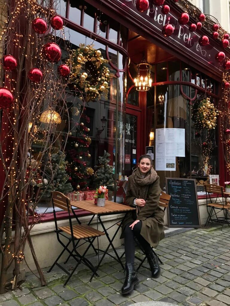 natali sitting on a terrace in front of a store decorated for christmas in bruges belgium