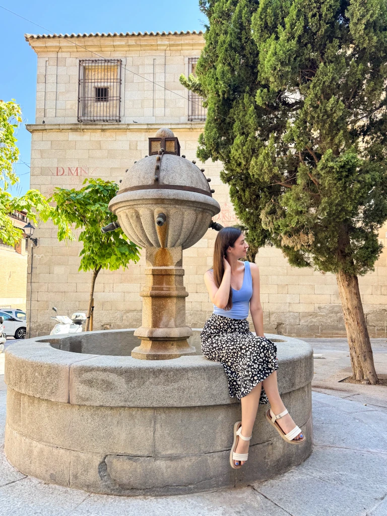 natali sitting on a stone fontain in the historic center of toledo